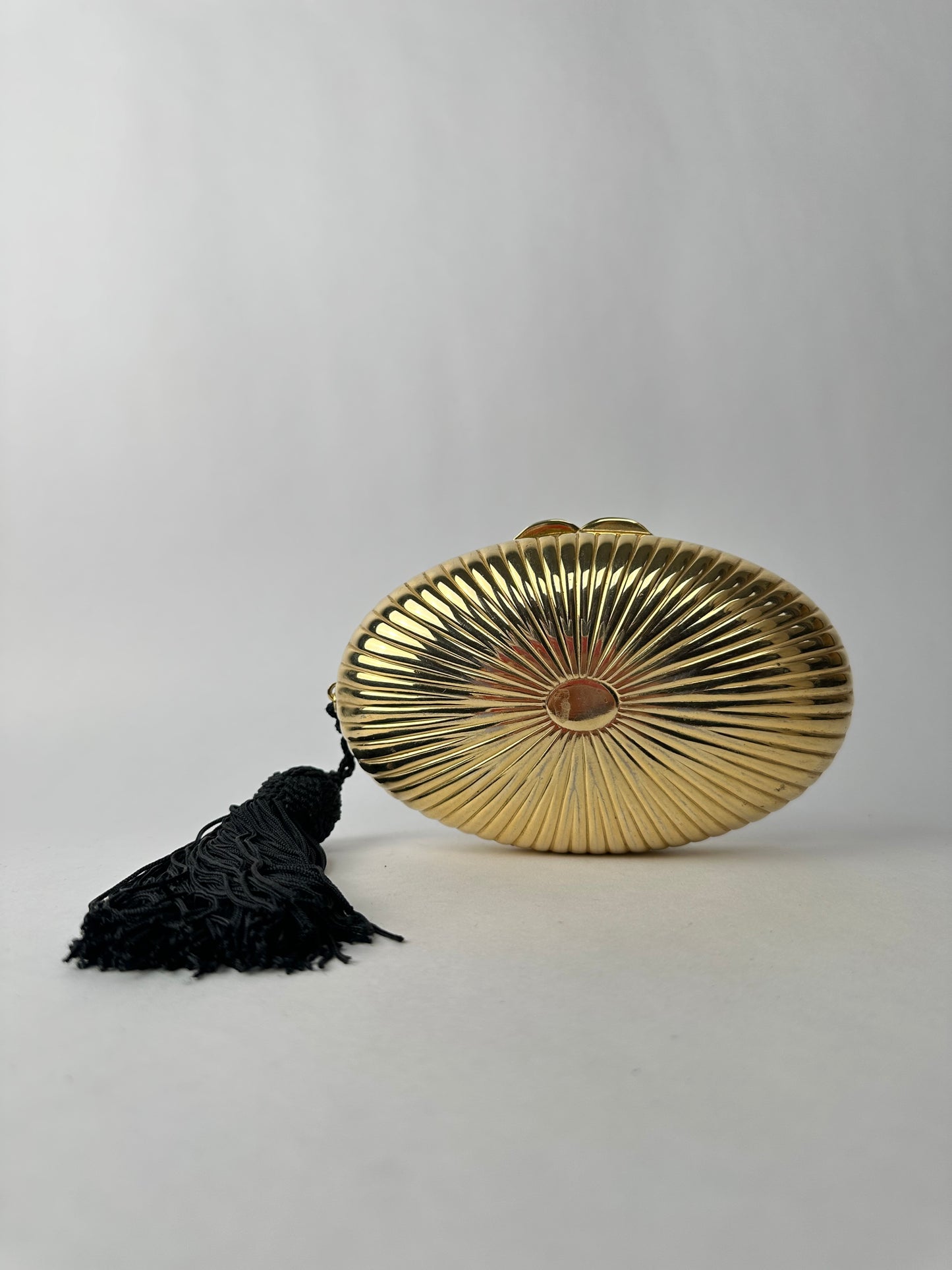 ANONYMOUS oval gilded metal minaudiere with black pompom detail