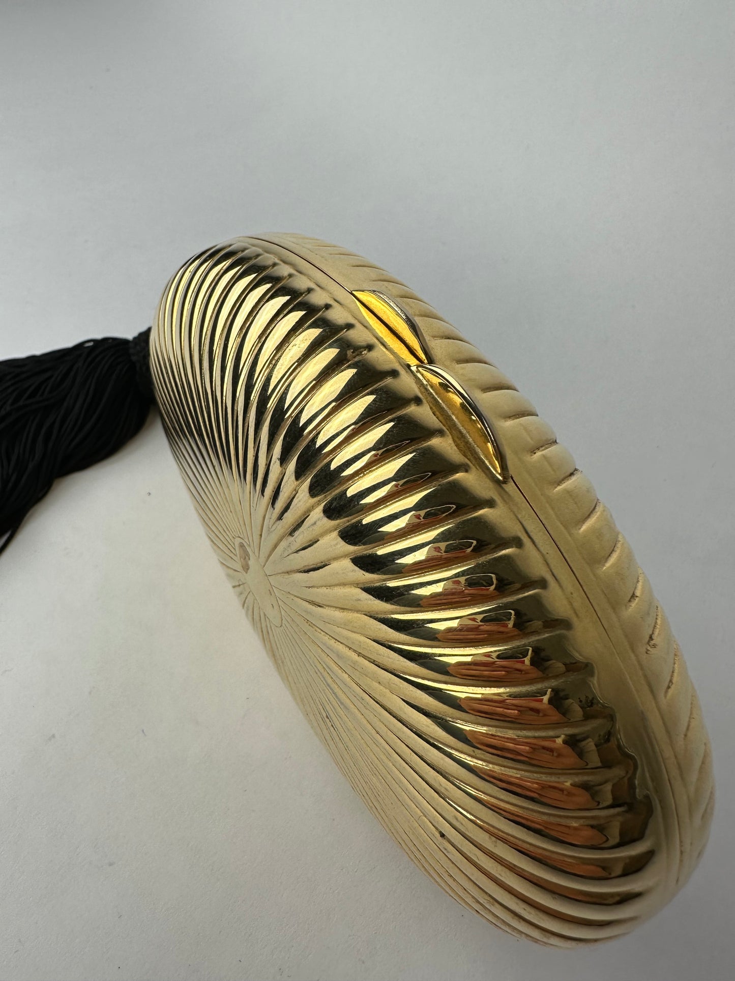 ANONYMOUS oval gilded metal minaudiere with black pompom detail