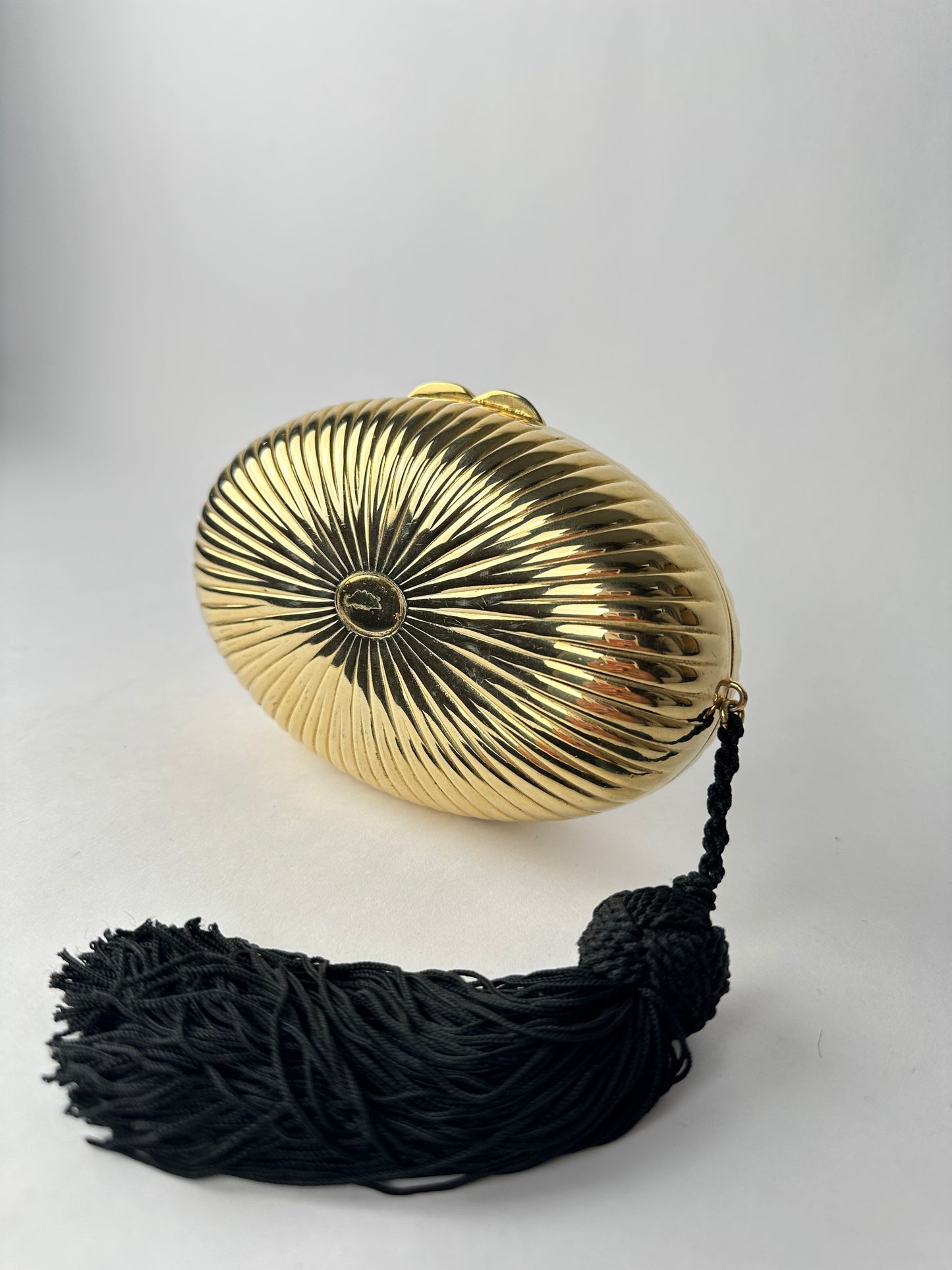 ANONYMOUS oval gilded metal minaudiere with black pompom detail