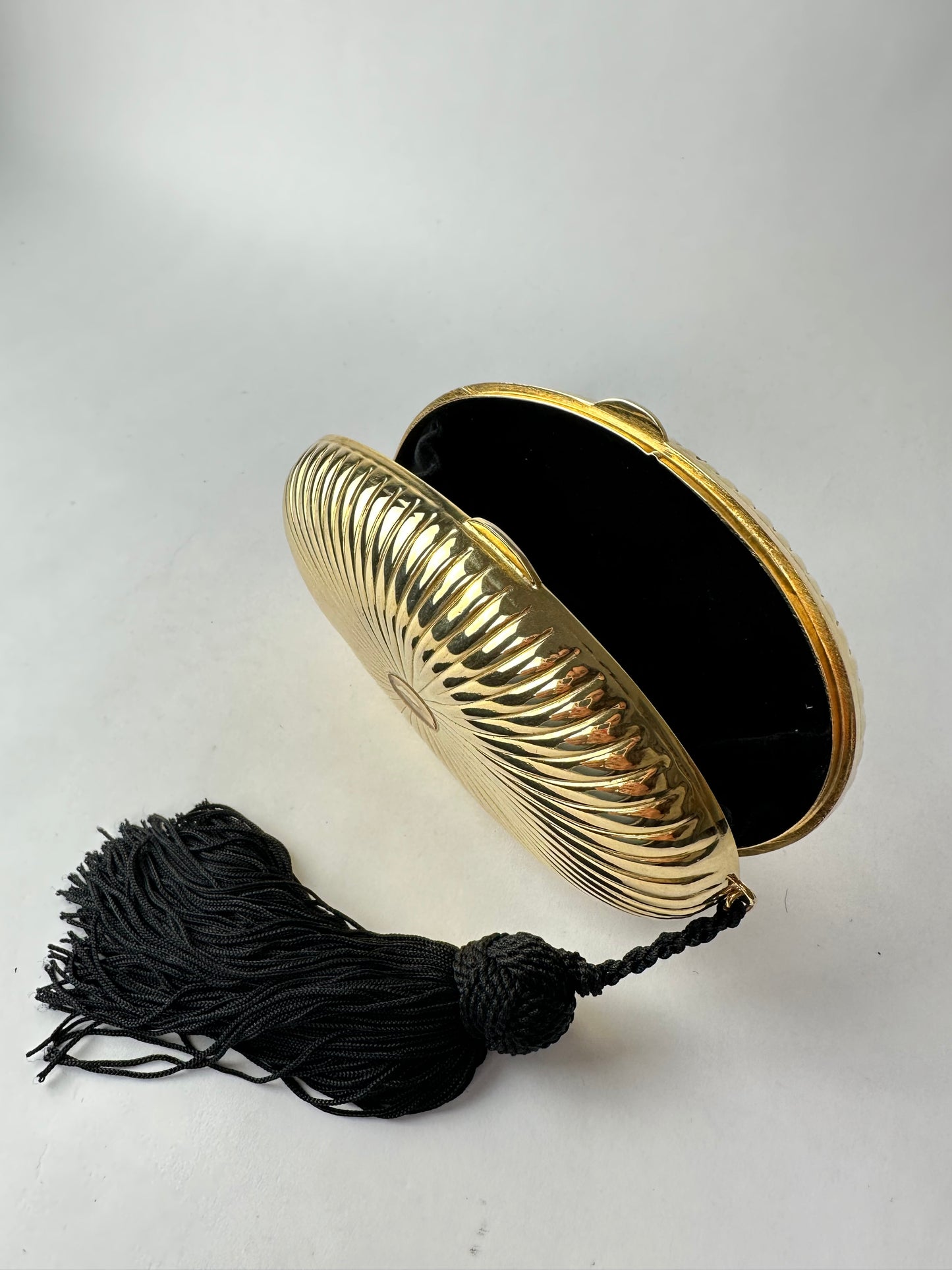 ANONYMOUS oval gilded metal minaudiere with black pompom detail