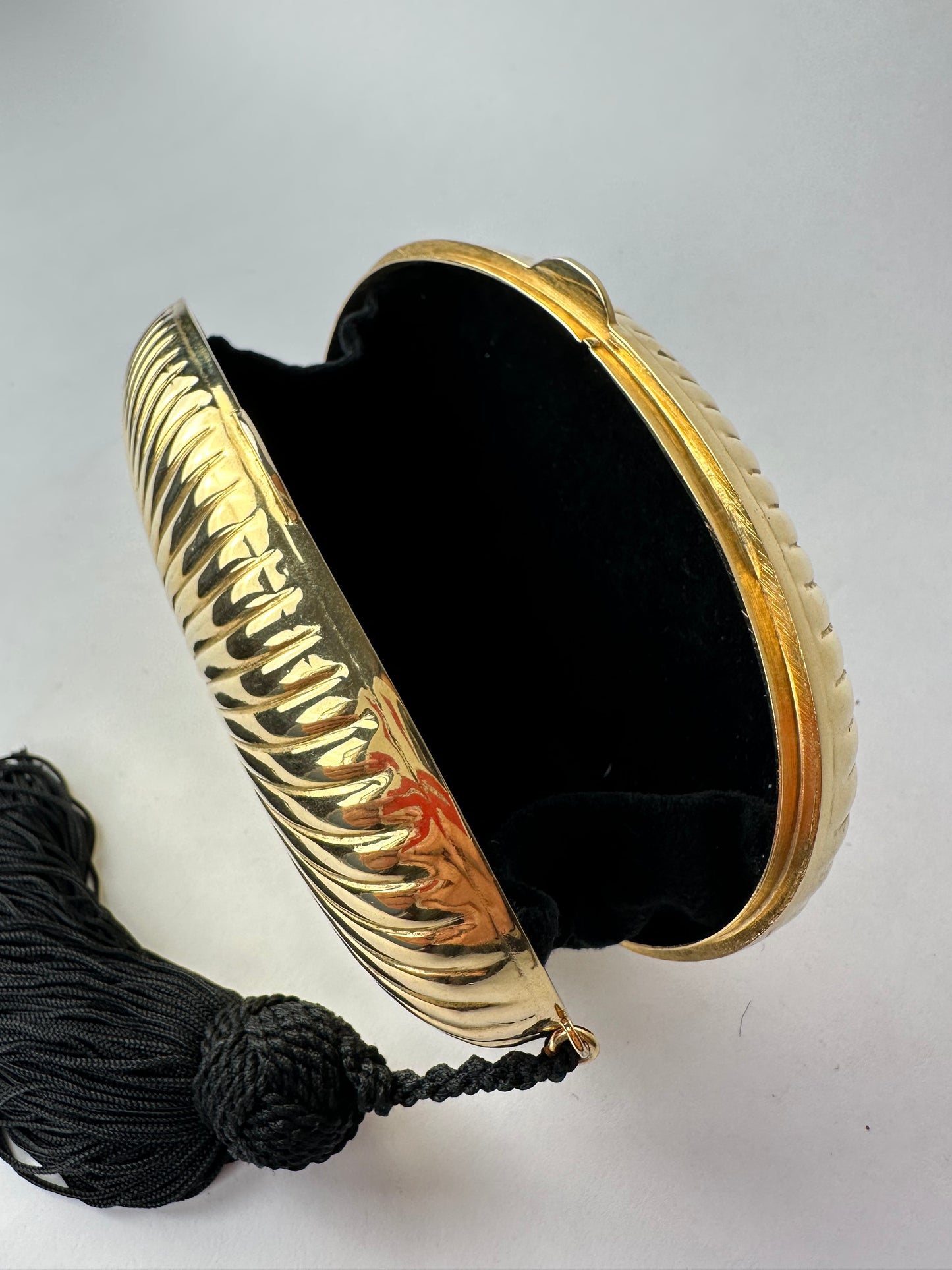 ANONYMOUS oval gilded metal minaudiere with black pompom detail