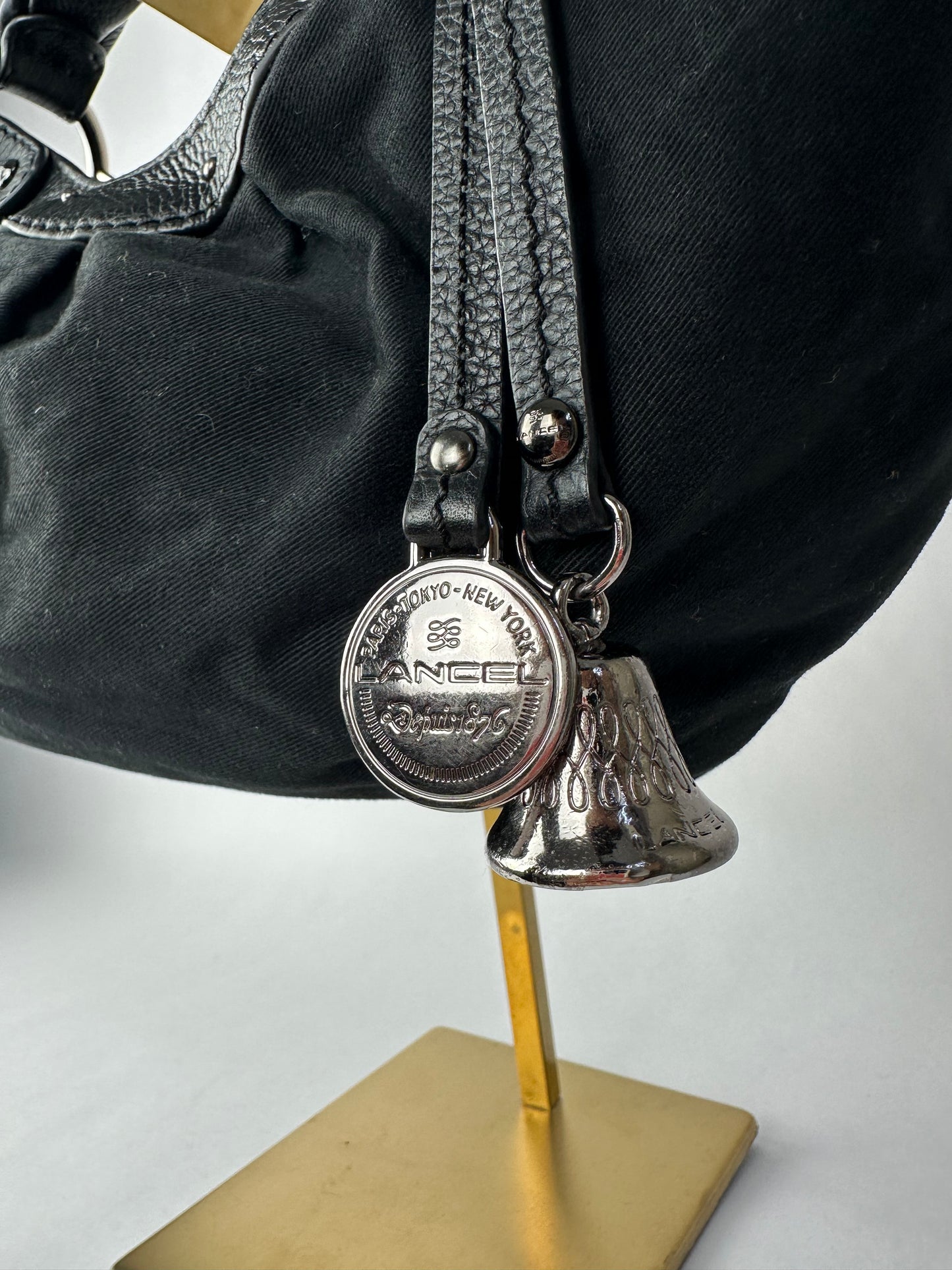 LANCEL small bag in cotton canvas and black grained leather decorated with a bell bag jewel and a signed coin, zipped handle.